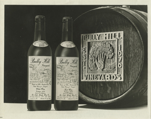 Two wine bottles in front of barrel of wine